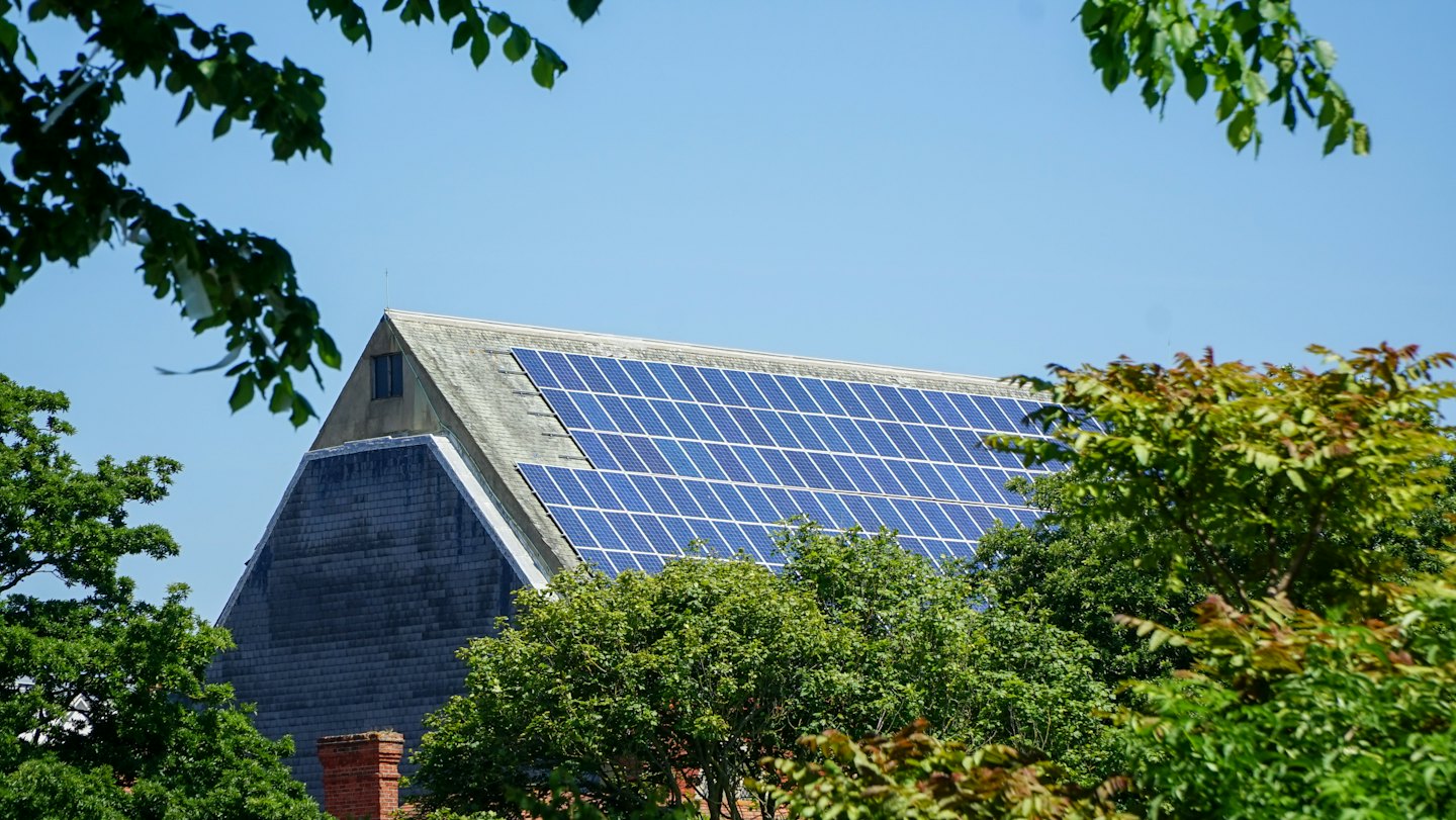 Blue solar panels installed on a grey shingle roof.