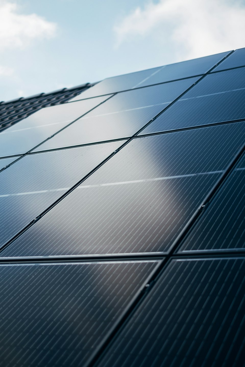Solar panels on a rooftop under a partly cloudy sky.