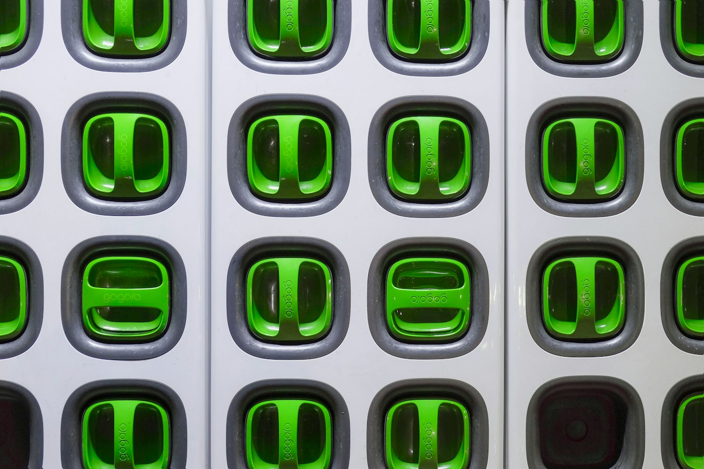 Green battery packs neatly arranged in a charging station.